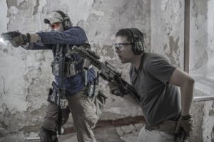 私服にプレートキャリアを着けて銃を構える2人の男性