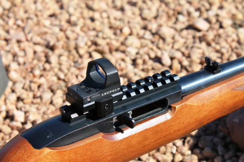ライフルのレールに載せたオープン型のドットサイト(LEUPOLD のロゴ入り・木のストックの銃)