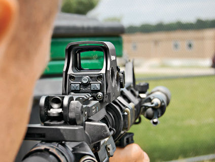 ホロサイトを載せたライフルを構えた人の肩越しに見たホロサイト（黒）