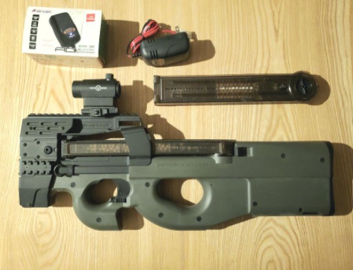 ドットサイトをトリガーの上あたりに載せたP90(マガジン・充電器・箱と並べたところ)
