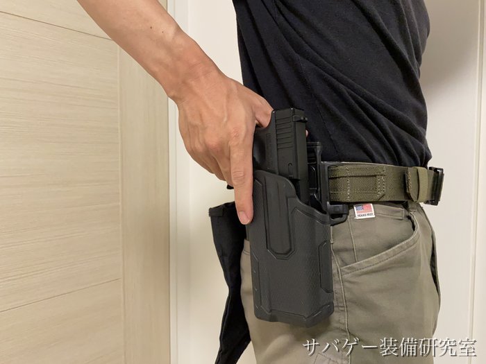 デューティーベルトに吊ったホルスターからハンドガンを抜こうとしているところ