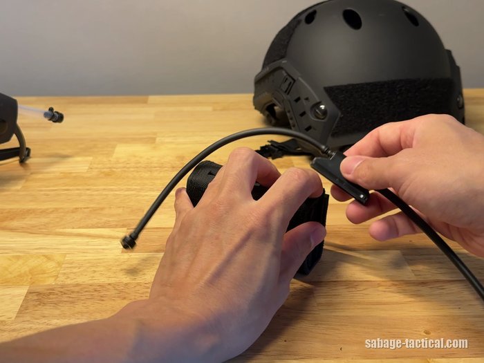 ヘルメットポーチの下の穴から、黒いチューブの付いたマニホールドを本体に付け直しているところ